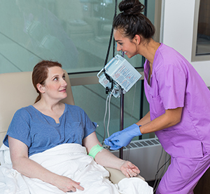 Healthcare provider caring for woman having infusion treatment.